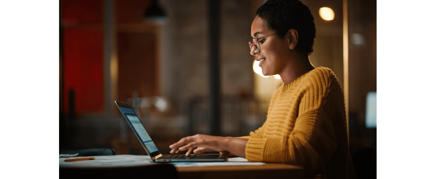 Woman smiling while typing on laptop